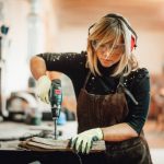 A female woodworker replacing an orbital sander's paper in a workshop